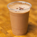 Plastic cup with a chocolate banana smoothie on a wooden surface.