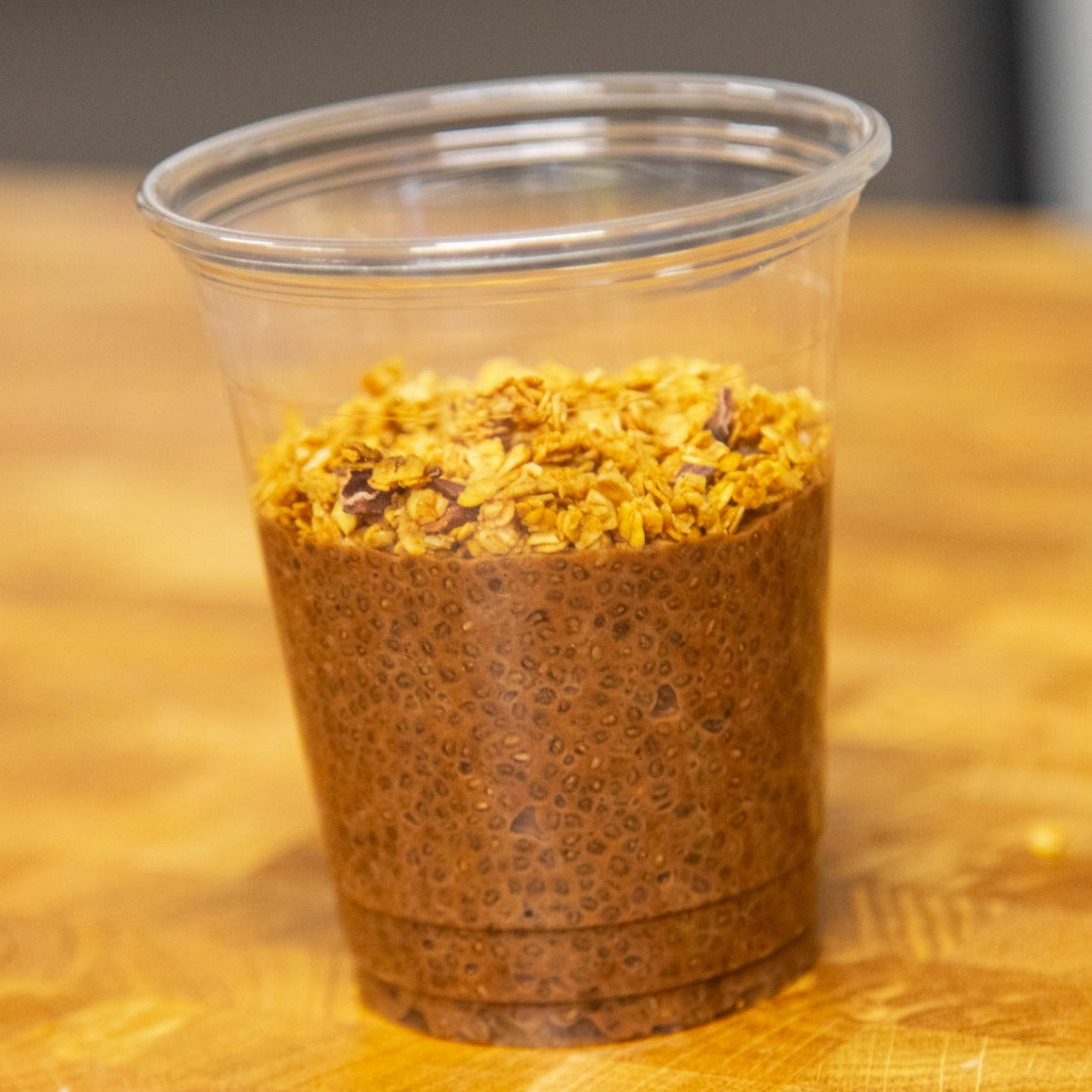 Clear plastic cup with Cold Brew Chia Pudding on a wooden surface