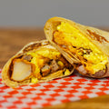 Breakfast burrito on a red and white checkered paper with a wooden background