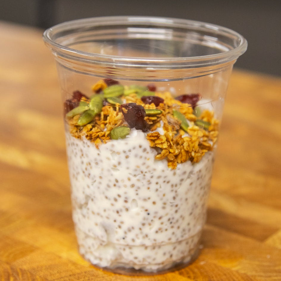 Clear plastic cup with layered chia pudding on a wooden surface