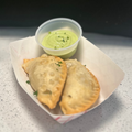 Empanadas with guacamole on a tray in front of a Nashville pillow.