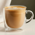 Clear glass mug with a matcha latte drink on a neutral background