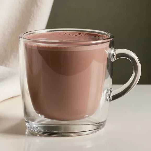 Glass mug with hot chocolate on a neutral background